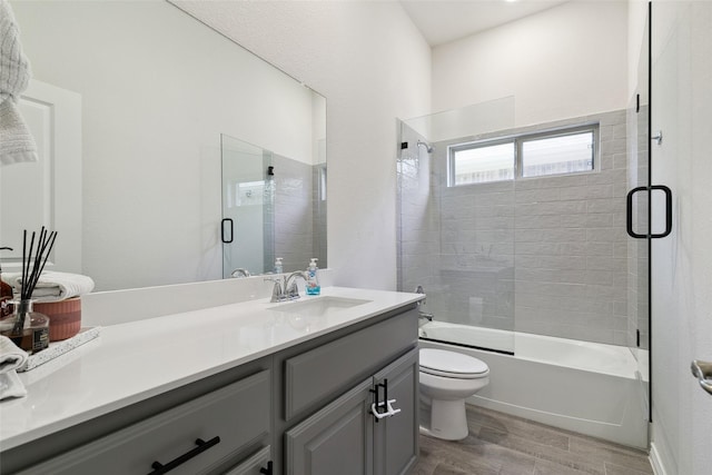 full bathroom with hardwood / wood-style flooring, vanity, toilet, and combined bath / shower with glass door