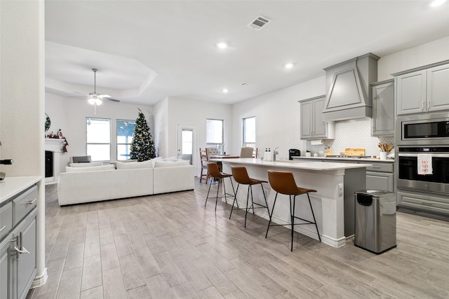 kitchen featuring a kitchen breakfast bar, a center island with sink, stainless steel appliances, and plenty of natural light