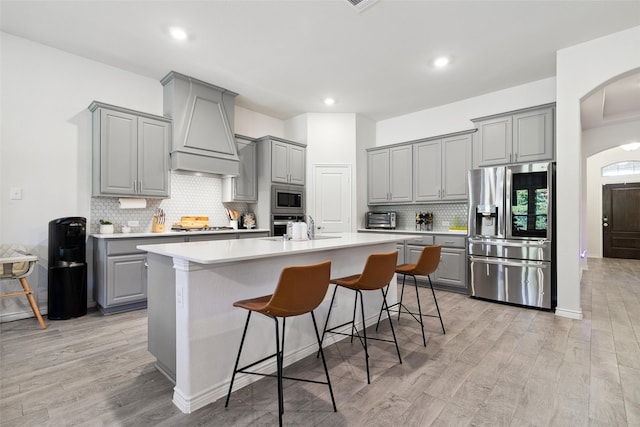 kitchen with gray cabinetry, an island with sink, and appliances with stainless steel finishes