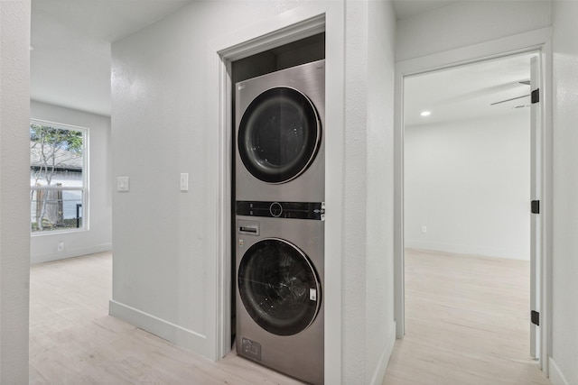 laundry room with light wood-type flooring and stacked washer and dryer