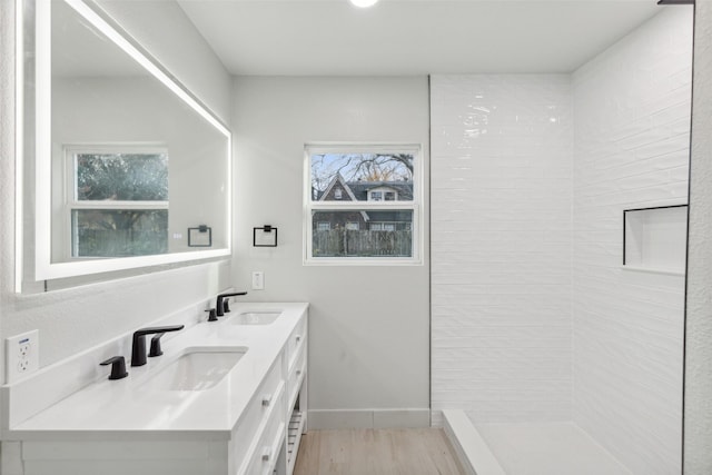 bathroom featuring hardwood / wood-style flooring, plenty of natural light, a tile shower, and vanity