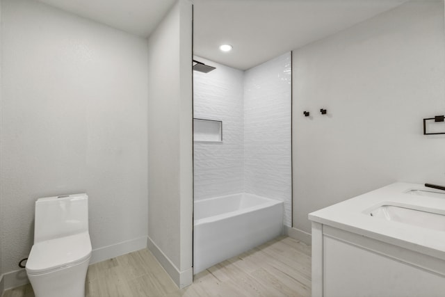 full bathroom with hardwood / wood-style flooring, vanity, tiled shower / bath combo, and toilet