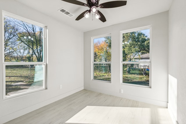 empty room with light hardwood / wood-style floors, plenty of natural light, and ceiling fan