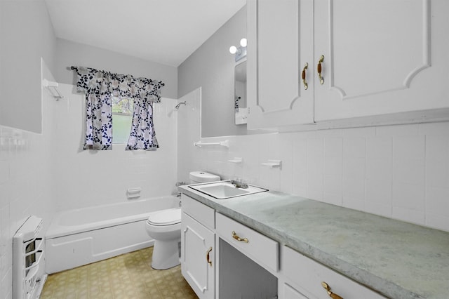 full bathroom with heating unit,  shower combination, toilet, vanity, and tile walls