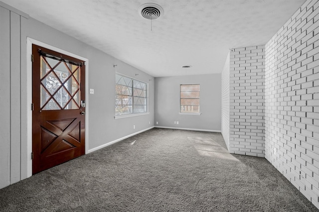 carpeted entrance foyer with brick wall and a textured ceiling