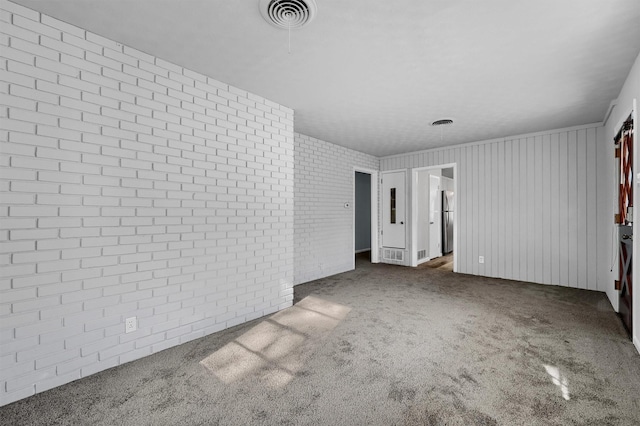 unfurnished bedroom with stainless steel fridge, dark carpet, and brick wall