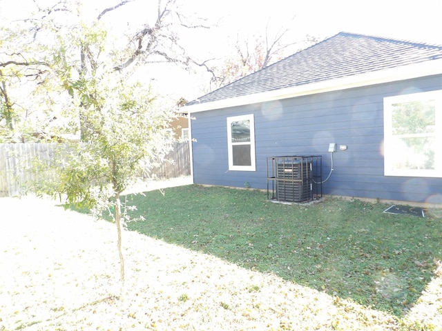 view of side of property featuring central AC unit and a lawn