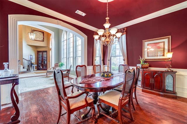 dining room with wood-type flooring, plenty of natural light, ornamental molding, and a chandelier