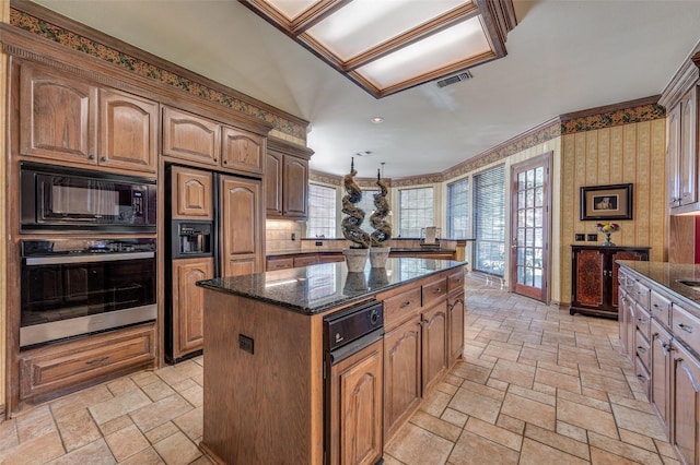 kitchen featuring built in appliances, a center island, and dark stone countertops