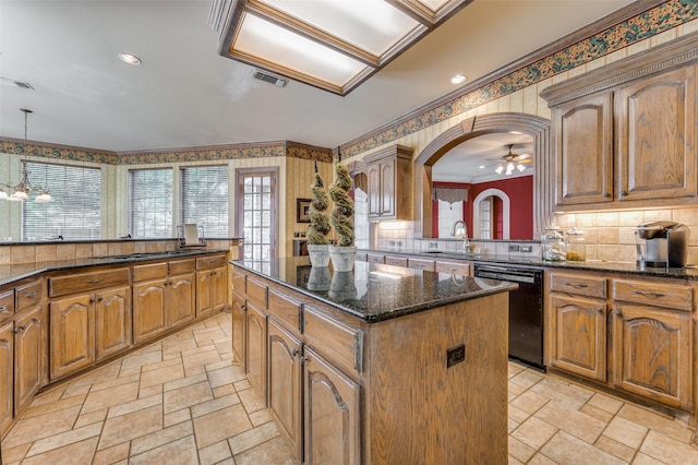 kitchen featuring a kitchen island, black dishwasher, sink, dark stone countertops, and ornamental molding