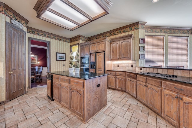 kitchen with built in appliances, ornamental molding, dark stone counters, and a kitchen island