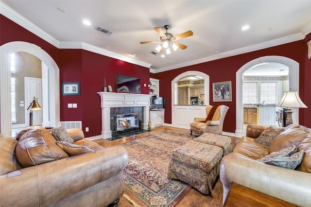 living room featuring hardwood / wood-style floors, crown molding, a high end fireplace, and ceiling fan