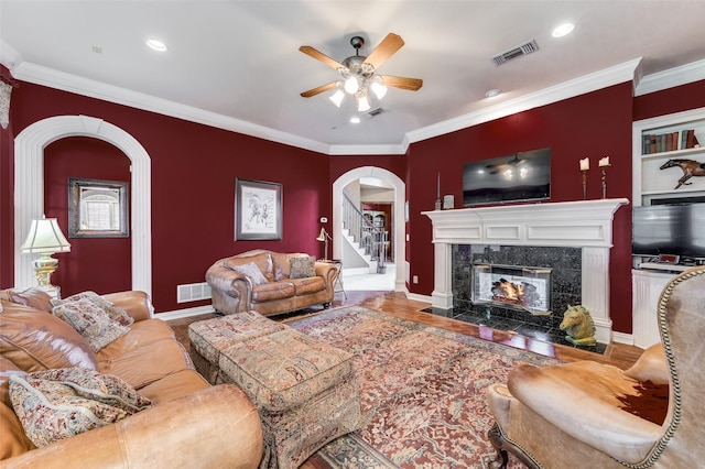 living room with crown molding, ceiling fan, and a fireplace