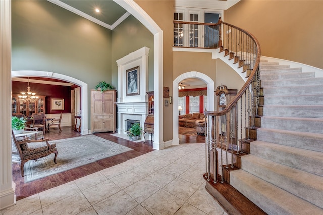 entrance foyer featuring a high ceiling, ornamental molding, light tile patterned floors, and an inviting chandelier