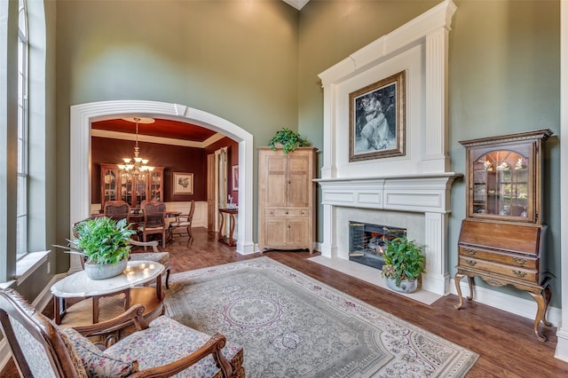 living room featuring a tile fireplace, dark hardwood / wood-style floors, a notable chandelier, and a towering ceiling