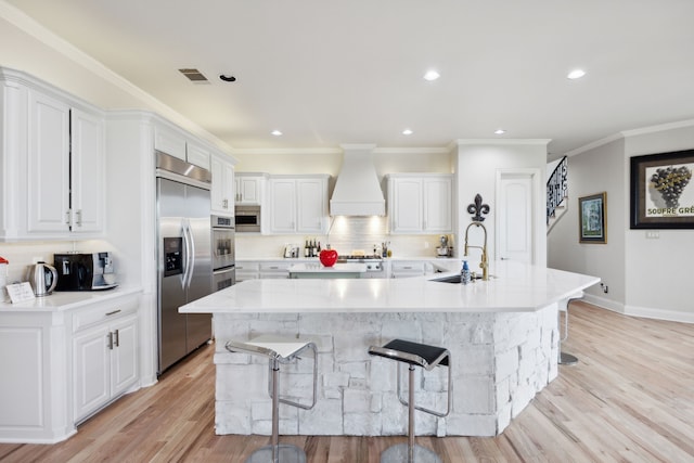 kitchen with a breakfast bar, a spacious island, sink, custom range hood, and white cabinetry