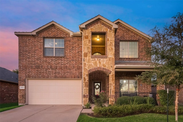 traditional-style house featuring a garage, concrete driveway, brick siding, and stone siding