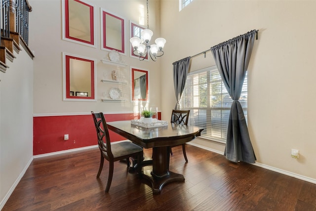 dining area featuring a chandelier, dark wood-type flooring, and a high ceiling