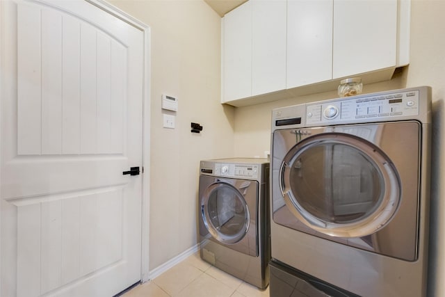 laundry room featuring separate washer and dryer, light tile patterned floors, and cabinets