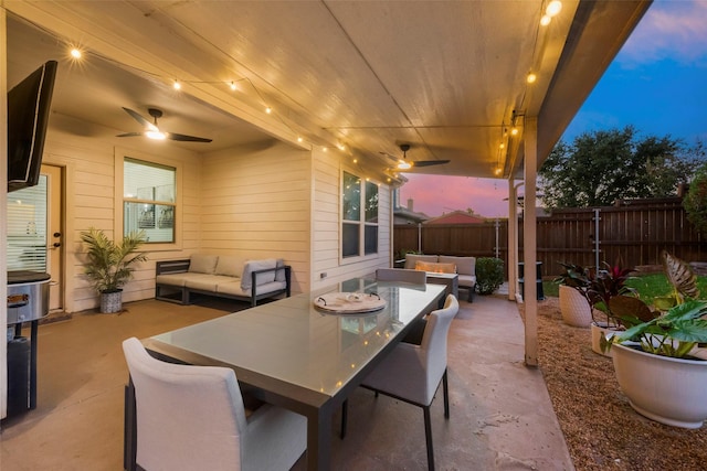 patio terrace at dusk with ceiling fan and an outdoor living space