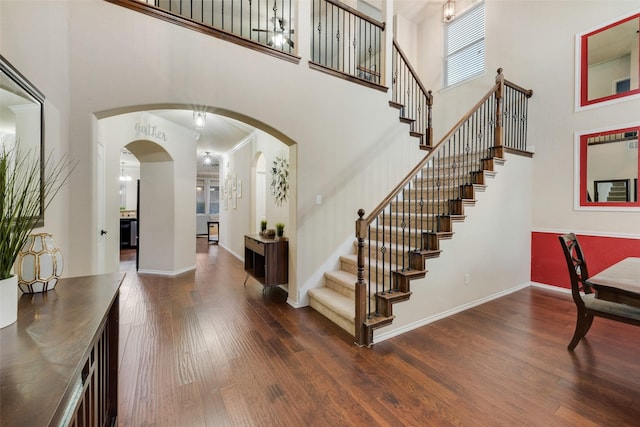 foyer with a towering ceiling, dark hardwood / wood-style floors, and ornamental molding