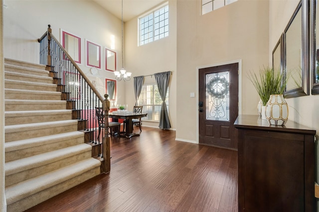 foyer featuring a towering ceiling, a chandelier, and hardwood / wood-style flooring