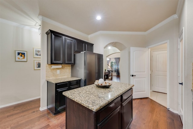 kitchen with dark hardwood / wood-style floors, a center island, ornamental molding, and stainless steel refrigerator