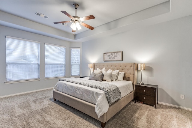 carpeted bedroom featuring ceiling fan and a tray ceiling