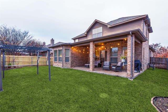 rear view of property featuring brick siding, a lawn, a fenced backyard, a patio area, and a pergola