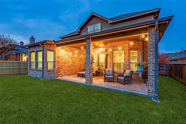 rear view of property with a yard, a patio area, and brick siding