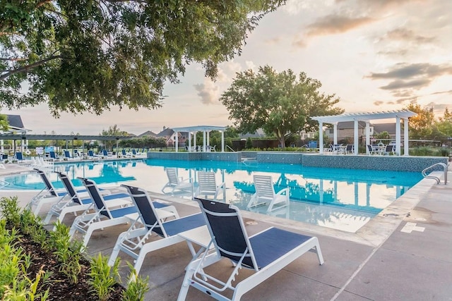 pool at dusk featuring a patio and a pergola