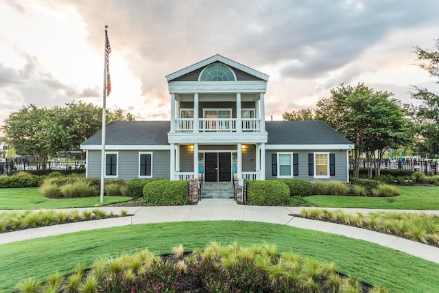 view of front of property featuring a balcony and a lawn