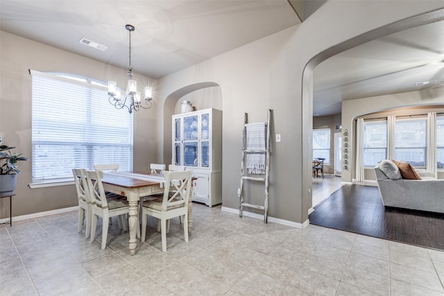 dining area featuring visible vents, arched walkways, baseboards, and a chandelier