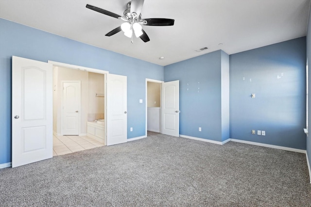 unfurnished bedroom featuring ceiling fan, light colored carpet, and ensuite bath