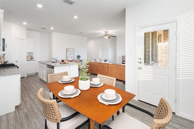 dining room with light hardwood / wood-style floors, ceiling fan, and sink