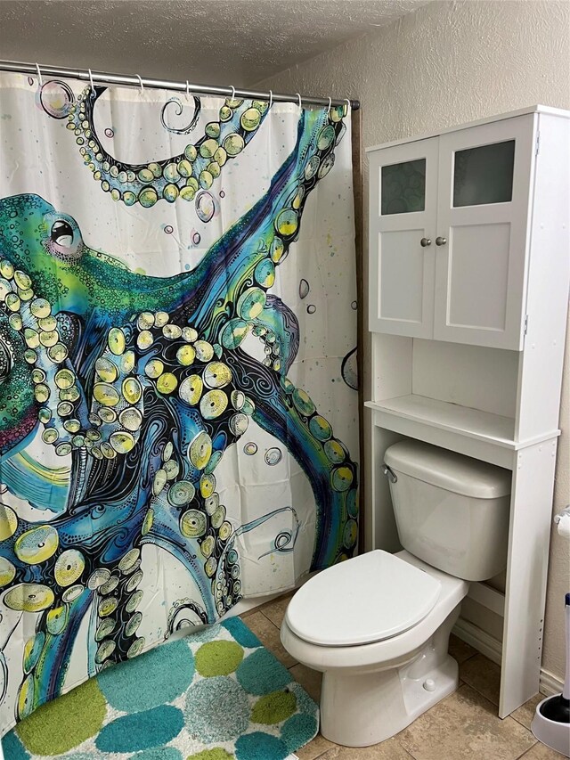 bathroom featuring tile patterned flooring, a textured ceiling, and toilet