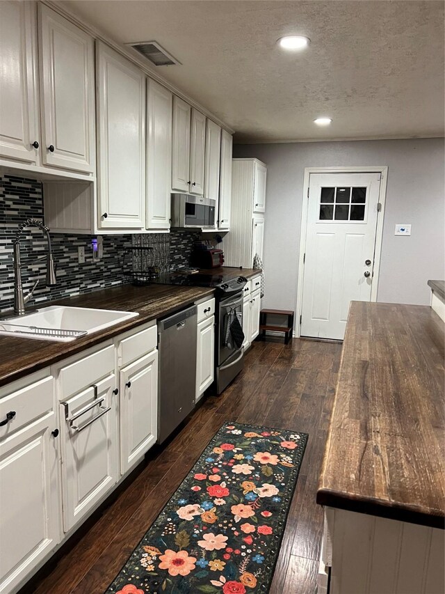 kitchen with backsplash, dark wood-type flooring, sink, white cabinetry, and stainless steel appliances