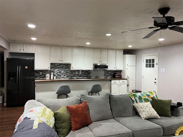 living room with ceiling fan, sink, dark wood-type flooring, and a textured ceiling