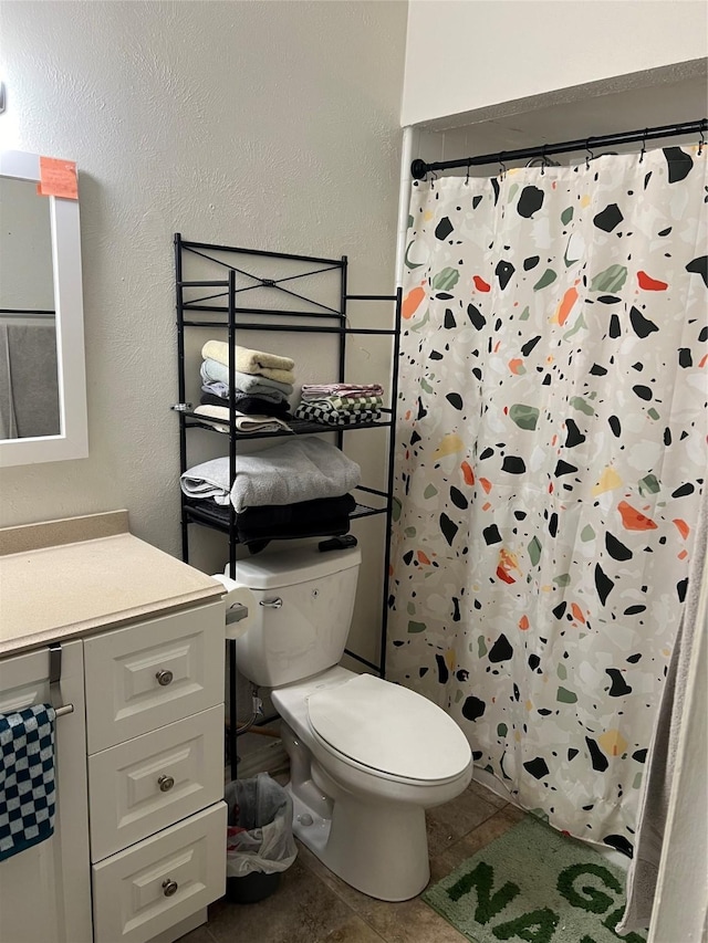 bathroom with tile patterned floors, vanity, toilet, and walk in shower