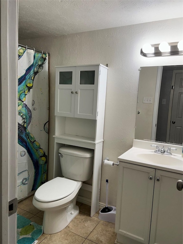 bathroom with tile patterned floors, vanity, toilet, and a textured ceiling