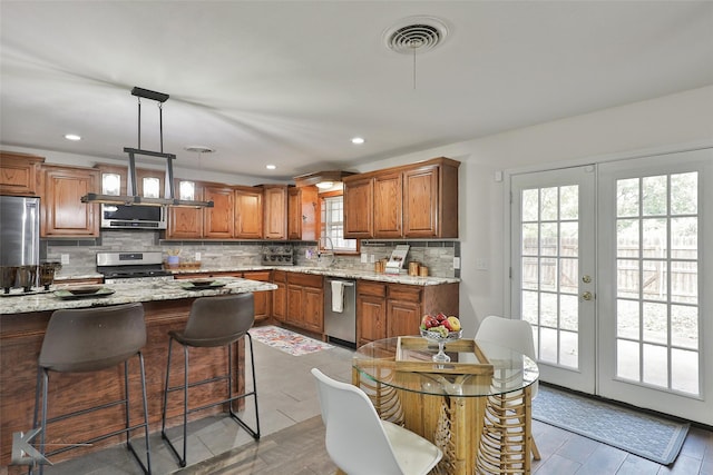 kitchen with french doors, stainless steel appliances, a wealth of natural light, and pendant lighting