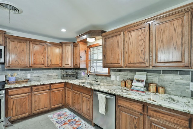 kitchen with sink, stainless steel appliances, light stone counters, decorative backsplash, and light tile patterned flooring