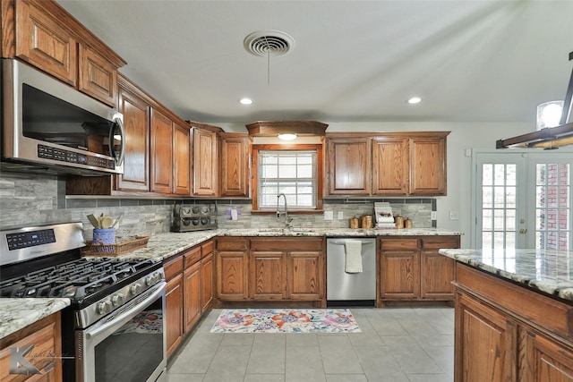 kitchen with light stone counters, a healthy amount of sunlight, sink, and stainless steel appliances