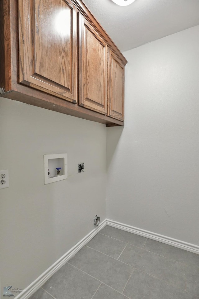 washroom featuring cabinets, hookup for a washing machine, dark tile patterned flooring, and hookup for an electric dryer