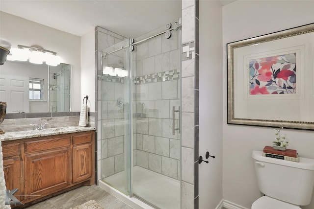 bathroom featuring vanity, toilet, and a shower with shower door