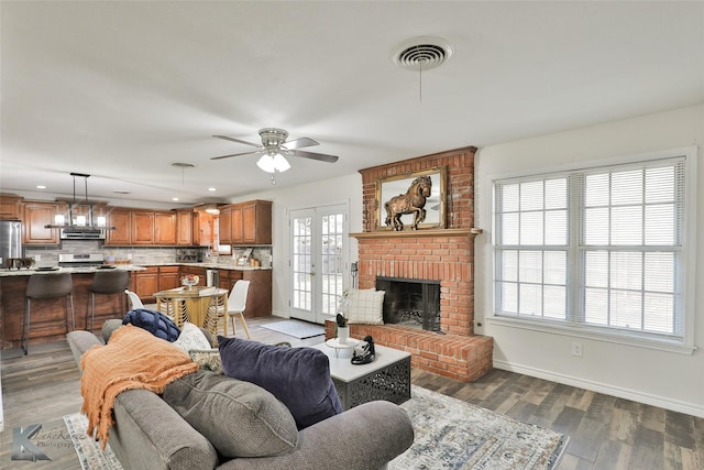 living room featuring ceiling fan, wood-type flooring, a fireplace, and a wealth of natural light