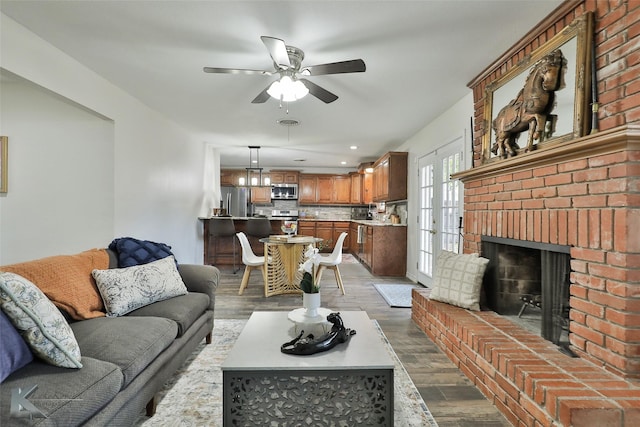 living room featuring a fireplace, wood-type flooring, and ceiling fan