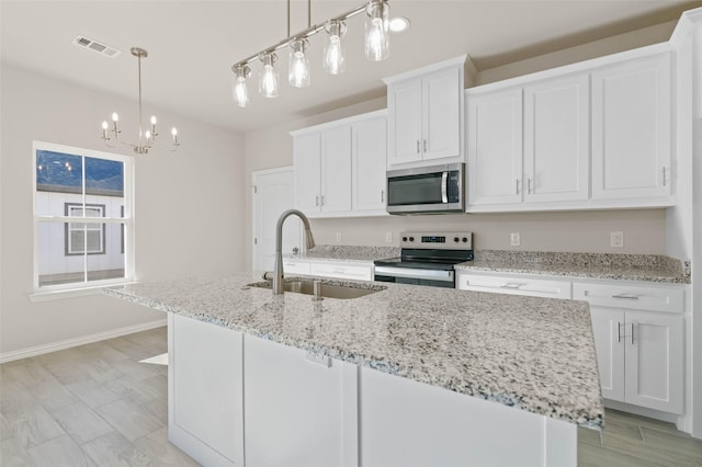 kitchen featuring white cabinets, sink, stainless steel appliances, and a center island with sink