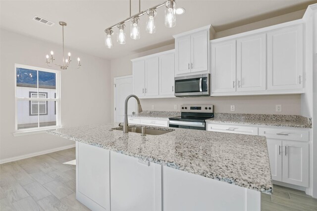 kitchen featuring white cabinetry, appliances with stainless steel finishes, a kitchen island with sink, and sink