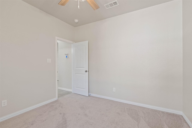 spare room with ceiling fan and light carpet